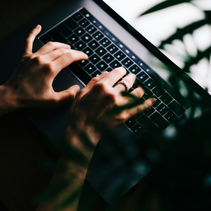 Woman typing on laptop keyboard at the night, close-up.